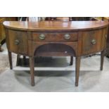 A Georgian mahogany demi-lune sideboard fitted with a symmetrical arrangement of drawers and