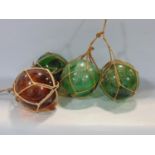 Four glass fishermans net floats, three in green, the other in brown