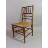 An Arts & Crafts child's chair with turned spindle back over a rush seat