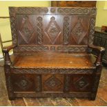 An old English oak box settle, panelled framework, rising lid, shaped arms and set beneath a further