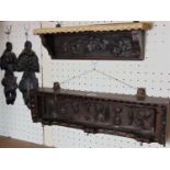 A carved mahogany wall bracket supporting three brass hooks with carved character detail within an