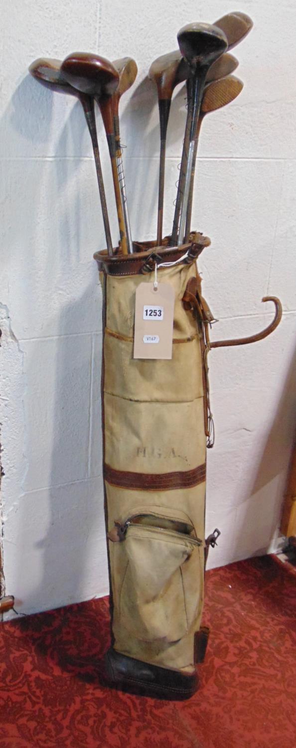 A vintage canvas and leather banded golf bag containing a number of vintage golf clubs