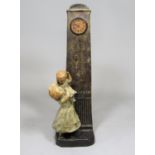 Austrian figural ceramic clock in the form of a mother holding a child beneath a tall Grandfather