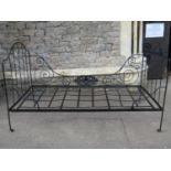 A antique ironwork folding single bedstead with arched head and footboard, decorative scroll and