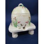A 19th century Belleek honey pot and cover in the form of a bee skep raised on a rustic three legged