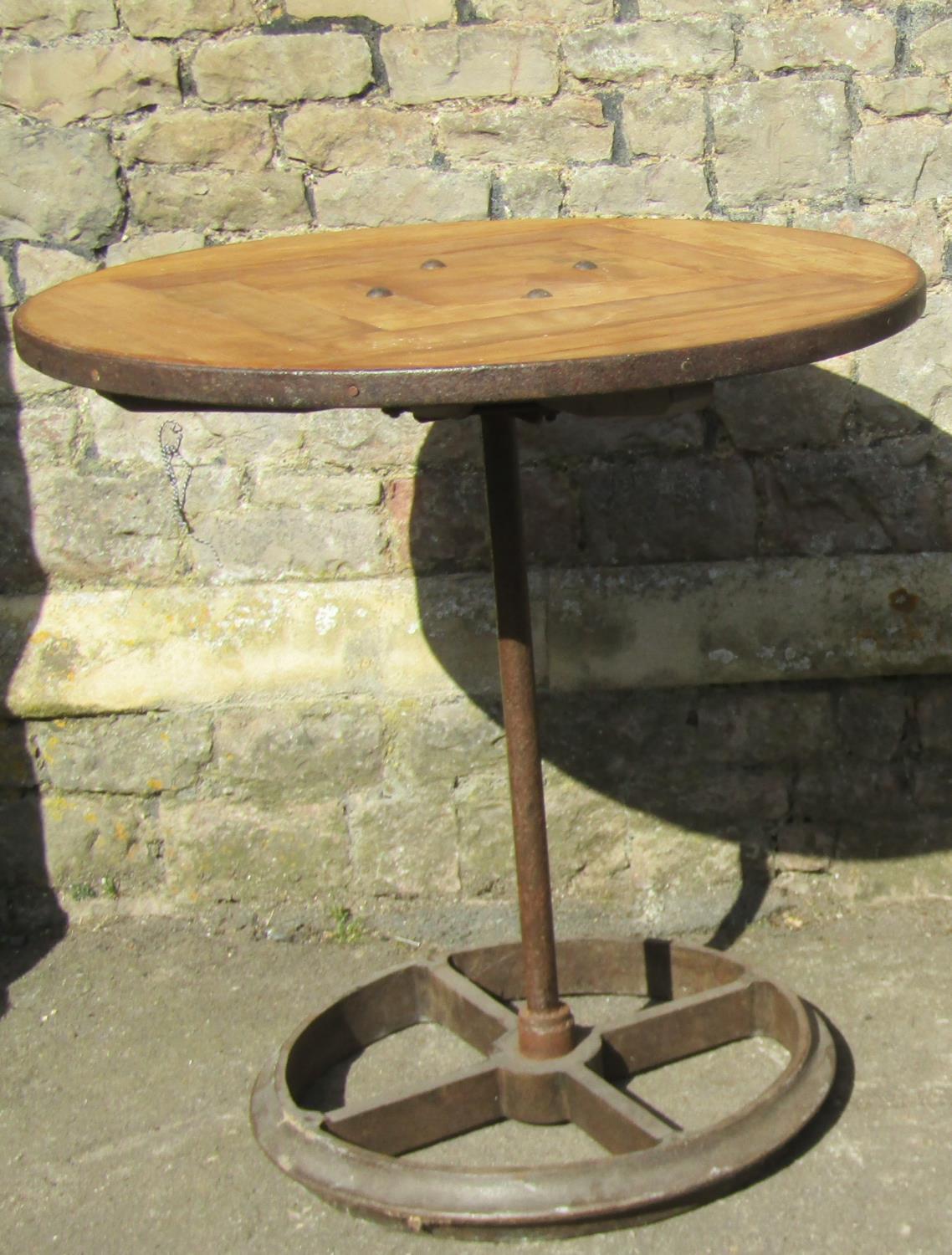 An industrial style steam punk bistro table, the circular pine segmented top with iron rim, raised