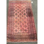 Old Bokhara Baluchi rug with typical geometric design upon a washed red ground, 220 x 125 cm