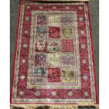 A Kashmir rug with panelled design with foliate borders upon a red ground, 170 x 120 cm