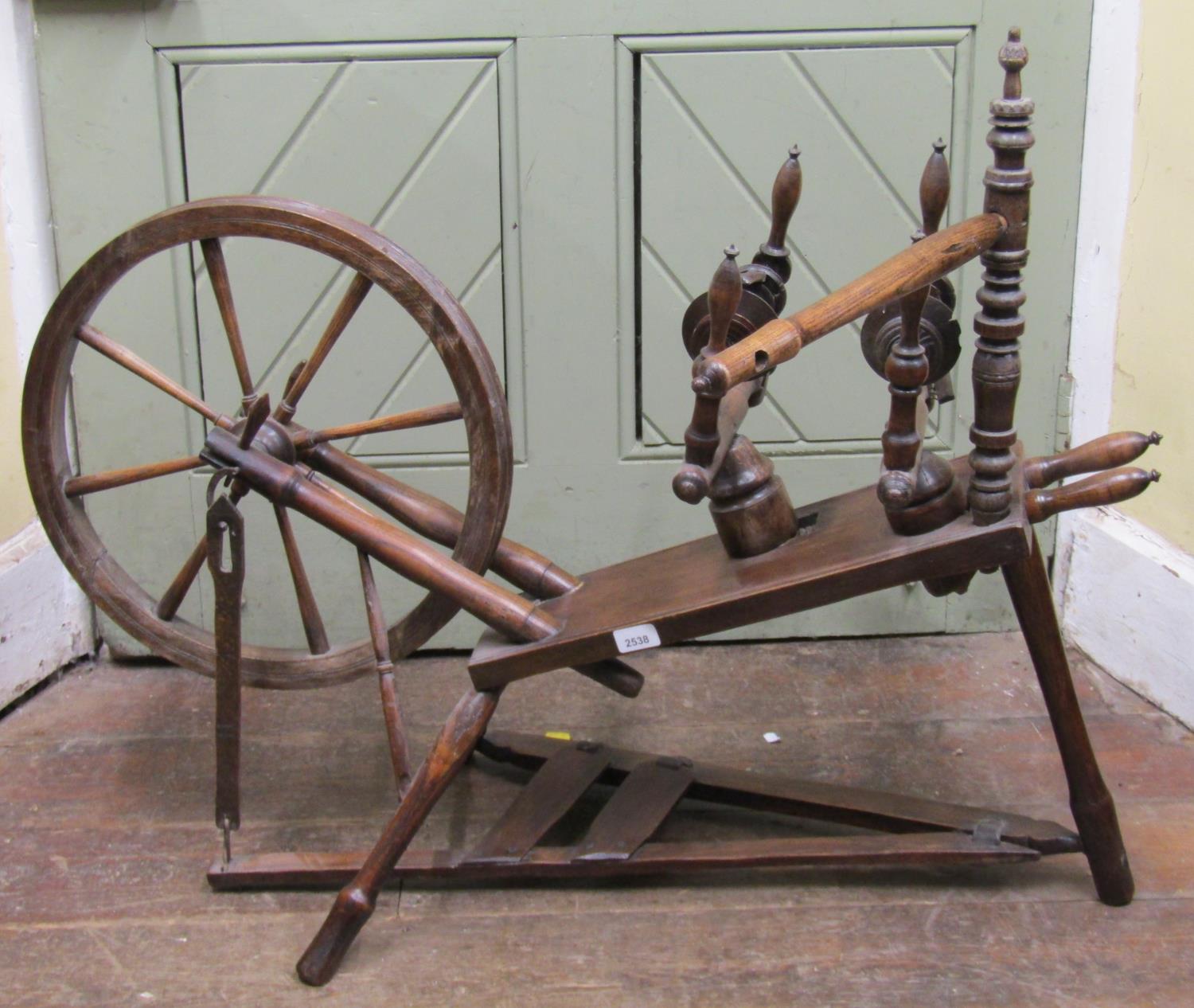 An antique spinning wheel in mixed woods including elm and beechwood, with turned spindles, 110cm