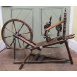 An antique spinning wheel in mixed woods including elm and beechwood, with turned spindles, 110cm