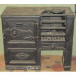 A small 19th century cast iron range partially enclosed by a single oven door with decorative