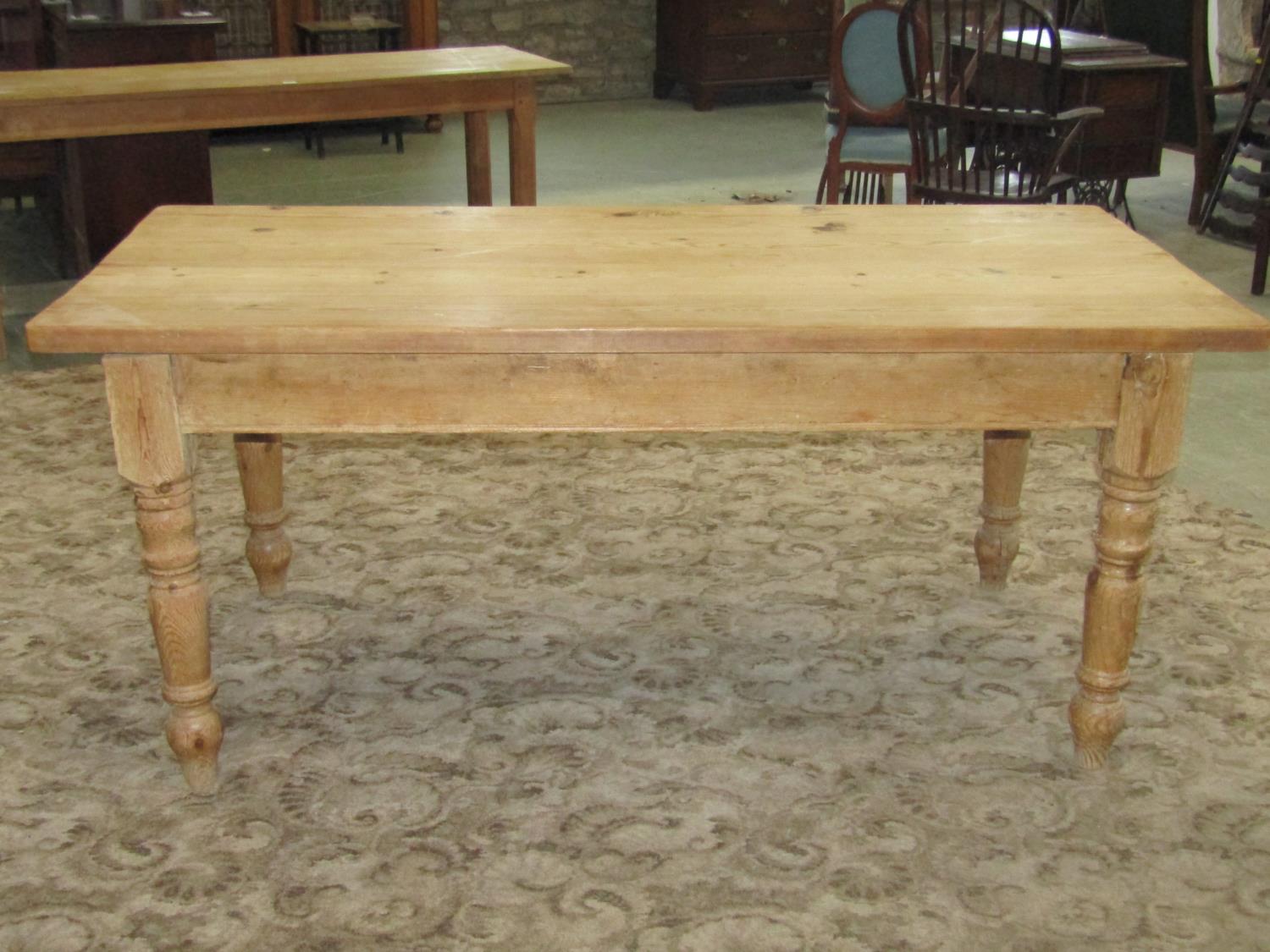 A reclaimed stripped pine farmhouse kitchen table of rectangular form raised on four ring turned and