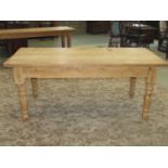 A reclaimed stripped pine farmhouse kitchen table of rectangular form raised on four ring turned and
