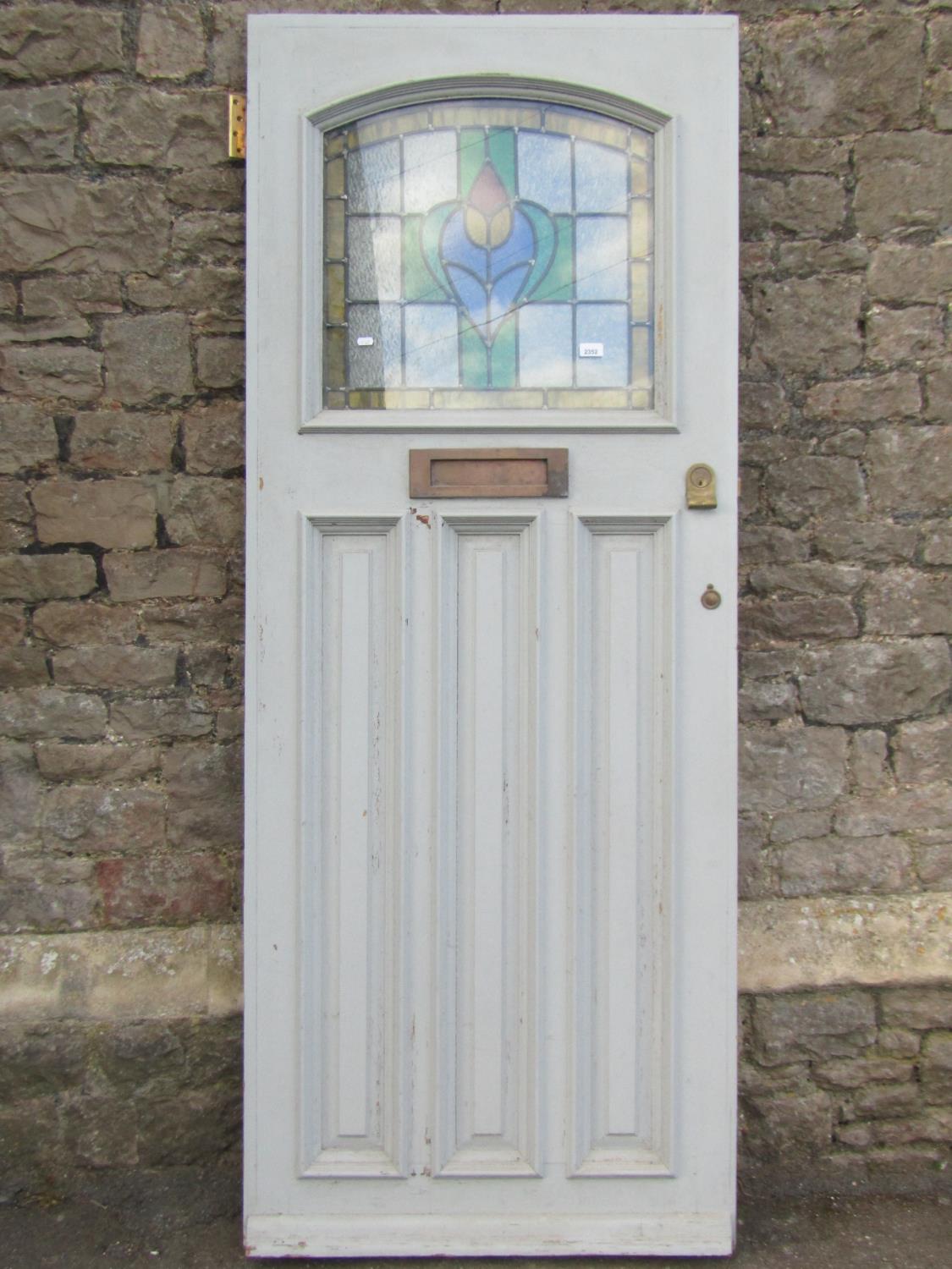 A reclaimed painted hardwood front door, enclosing an arched leaded light panel, over three