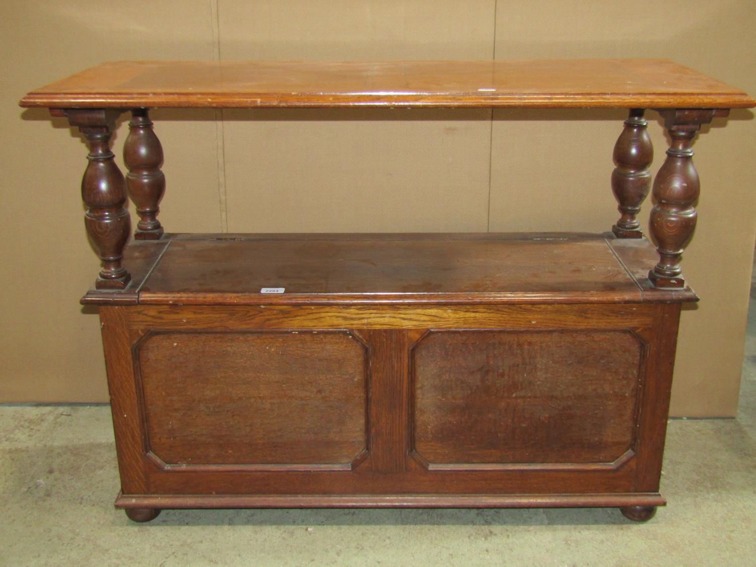 A 1920s narrow oak monks/hall bench, the rectangular sliding top raised on baluster supports over