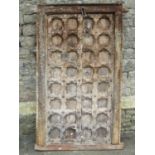 An antique weathered carved eastern panelled door and combined framework with repeating foliate