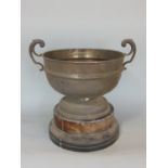 A silver plated rose bowl by Mappin & Webb with open scroll handles, raised on a timber base