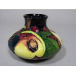 A Moorcroft pottery vase with fig, grape and other fruit detail on a dark blue ground, with