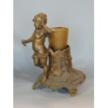 A gilt cast metal dish stand in the form of a naughty cherub next to a tree trunk, fitted with a