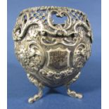 Cast silver egg shaped vase with floral scroll and other detail raised on three shaped supports,