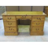 A contemporary pine kneehole dressing table/desk fitted with an arrangement of seven drawers with