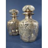 A pair of silver overlaid glass toilet water bottles with repeating foliate details, 12cm high