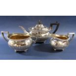 A three piece silver tea set with half fluted panels and gadrooned borders raised on ball feet,