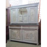 An antique two sectional buffet, enclosed by an arrangement of cupboards and doors with carved