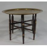 An Arabic, brass and timber occasional table, the circular top principally in brass, but inlaid with