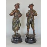 A pair of spelter figures of a boy and girl, he holding a birds nest, she a bouquet of flowers, 36cm