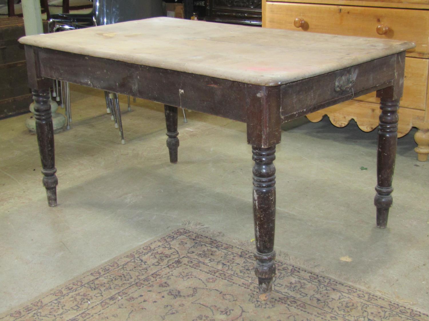 A Victorian scrub top pine kitchen table of rectangular form with moulded outline over an end frieze