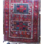 Good tribal village rug with geometric medallion design upon a deep red ground, 300 x 160 cm