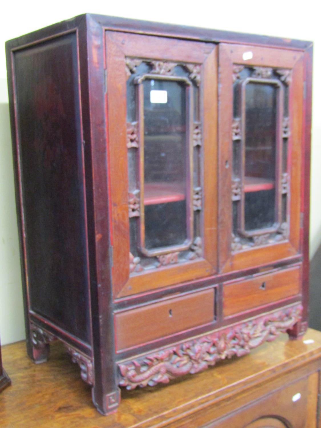 A 19th century Chinese side cupboard, enclosed by two glazed panelled doors over two frieze