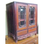 A 19th century Chinese side cupboard, enclosed by two glazed panelled doors over two frieze