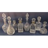 A collection of eight various cut glass decanters together with three leather cased sets of silver