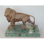 A cast figure of a lion upon a marble plinth