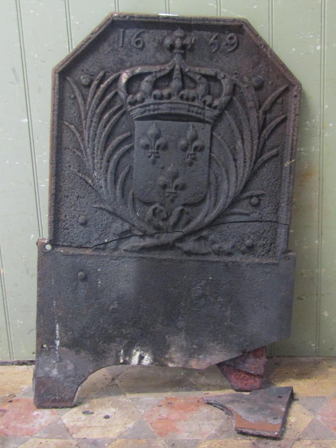 An antique cast iron fireback with canted corners, raised relief armorial shield with crown, dated