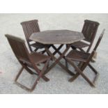 A teakwood folding garden table of octagonal form, 1m diameter approx, together with four folding