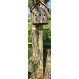 A traditional bird house in four divisions with rustic bark finish
