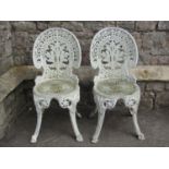 A pair of cast aluminium garden chairs with acanthus leaf backs raised on scrolled supports