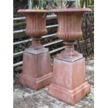 A pair of Regency style cast iron campana shaped urns raised on square tapering iron bases, 87 cm in
