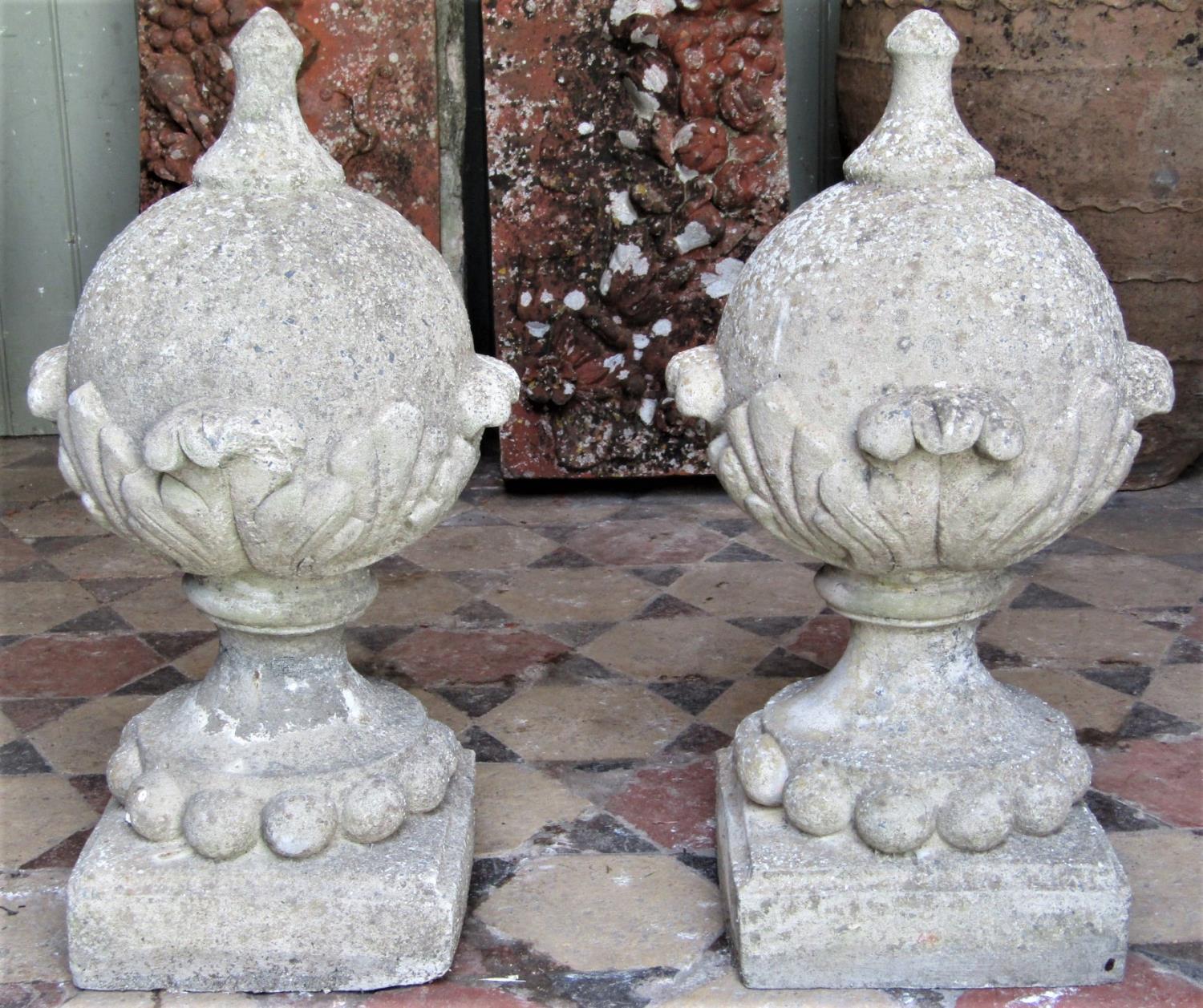 A pair of reclaimed garden finials globular with acanthus leaf detail raised on square cut bases, 55