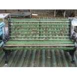 A Victorian three seat garden/park bench with weathered green painted timber lathes raised on a pair