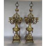 A good pair of brass four branch candelabra, with rococo style sconces, upon a faceted baluster