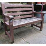 A stained and weathered teakwood two seat garden bench with slatted seat and back, labelled to