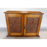 Edwardian oak smokers cabinet, the twin hinged doors with carved panels enclosing a fitted