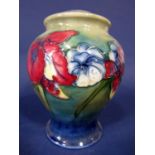 A Moorcroft table lamp base with blue and red iris decoration on a graduated green and blue ground