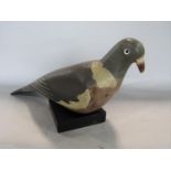 Folk art primitive painted decoy pigeon upon an associated black wooden plinth, 35cm long