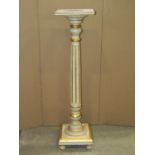 A torchere in the form of a classical column with fluted detail and painted and gilded finish, the