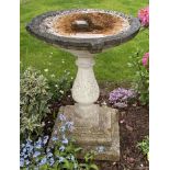 A reclaimed three sectional bird bath of circular form raised on a baluster shaped pillar and